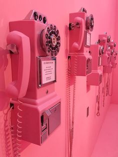 pink telephones are lined up against the wall in a room that looks like it has been painted pink