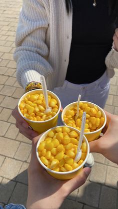 three people holding bowls of food with straws in them