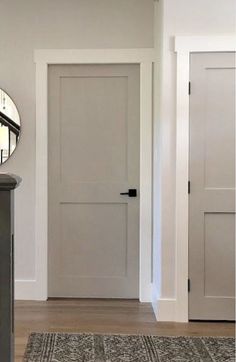 an entryway with a mirror and rug on the floor in front of two doors