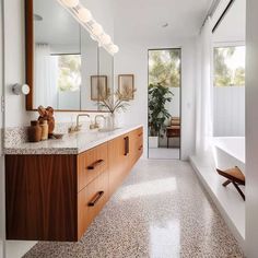 a large bathroom with marble counter tops and wooden cabinetry, along with a bathtub