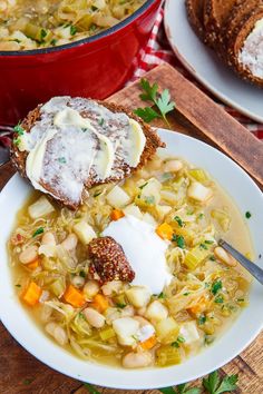 a bowl of soup with bread and sour cream on the top, next to another bowl of soup