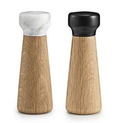 two salt and pepper shakers with black tops on a white background, one in the foreground