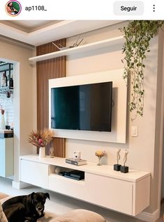 a dog laying on the floor in front of a flat screen tv mounted to a wall