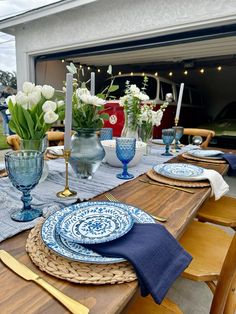 the table is set with blue and white plates, silverware, and flowers in vases