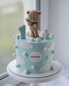 a blue and white cake with a teddy bear on top