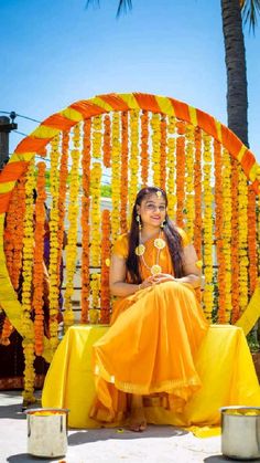 a woman sitting in front of an orange and yellow decoration