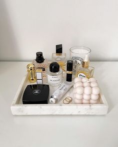 an assortment of beauty products displayed on a marble tray with white walls in the background