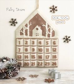 a cross stitch christmas ornament hanging on a wall with snowflakes around it