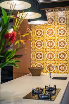 a kitchen counter with a sink, stove and lights on it in front of a colorful wallpaper