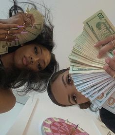 two women are holding money in front of their faces and the woman has her hands on top of each other's head