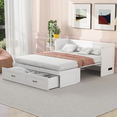 a white bed with drawers underneath it in a room next to a chair and table