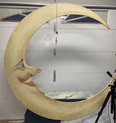 a large wooden moon sitting on top of a table in front of a camera tripod