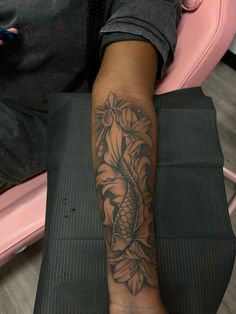 a person sitting in a chair with a tattoo on their arm and the other leg