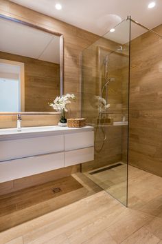 a bathroom with a glass shower door, sink and mirror on the wall next to it