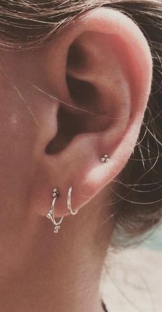 a close up of a person's ear with two piercings on it and one behind the ear