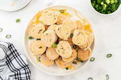 a white plate topped with rolls covered in cheese next to green beans and sauces