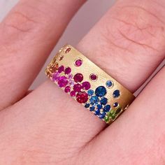 This lovely rainbow confetti is dripping with 1.36 carats of sapphires, rubies, and tsavorites and makes a bold statement as a cigar band. All the genuine gemstones are like a galaxy of flush set and the gold is textured. This band ring is breathtakingly colorful! Accented by lovely 14 karat brushed yellow gold with 1.36 carats total weight of genuine gemstones, this ring is amazing by itself and in a stack! The details for this beautiful ring are listed below:Metal Quality: 14K Gold (Available Confetti Ring, Galaxy Rainbow, Gold Jewellery India, Rainbow Confetti, Bezel Set Engagement Ring, Heirlooms Jewelry, Rainbow Jewelry, Gold Rings Fashion, Unique Wedding Bands