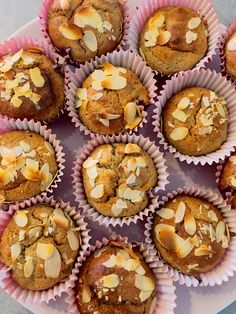 there are many muffins in the paper cups on the plate with almonds