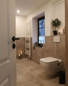 a white toilet sitting next to a window in a bathroom under a radiator