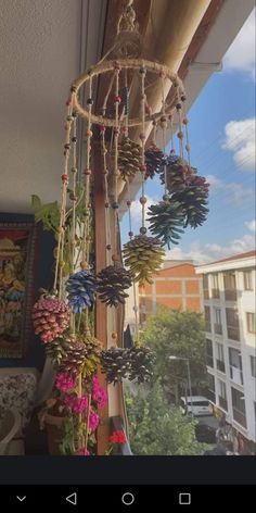 a chandelier made out of pine cones hanging from the side of a window