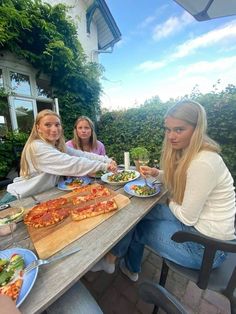 three women sitting at a table eating pizza