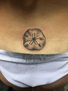 a woman's stomach with a sand dollar tattoo on it