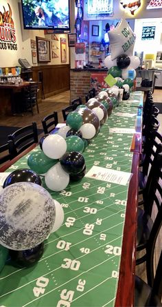 a long table with balloons and footballs on it at a sports themed party in a fast food restaurant