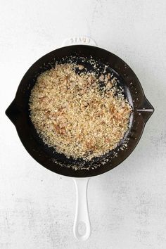 a skillet filled with food sitting on top of a white counter next to a knife