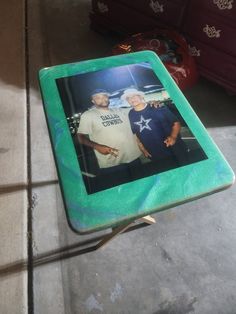 two men are standing next to each other in front of a photo on a table