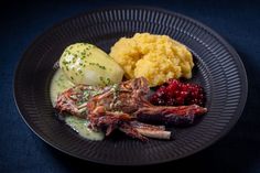 a black plate topped with meat, mashed potatoes and cranberry sauce