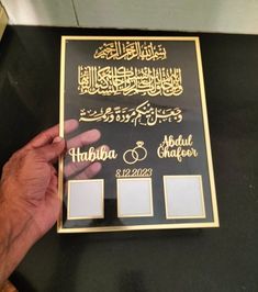 a person holding up a plaque with arabic writing on it