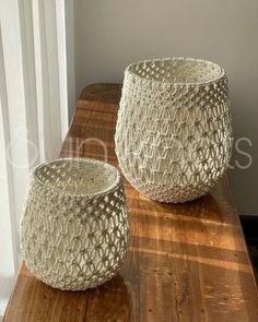 two white baskets sitting on top of a wooden table