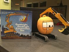 an orange pumpkin sitting on top of a counter next to a book and construction site