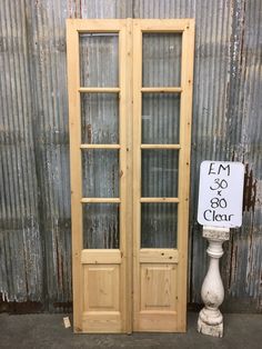 two wooden doors sitting next to each other in front of a metal wall with a sign on it