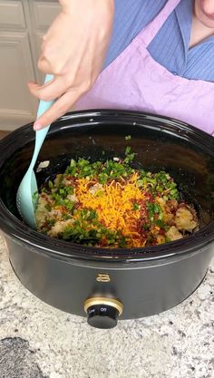 a woman is stirring food in a slow cooker