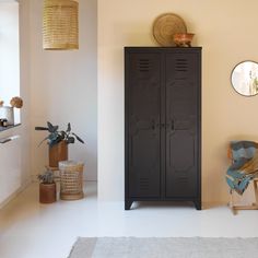 a black cabinet sitting next to a chair in a room with white floors and walls