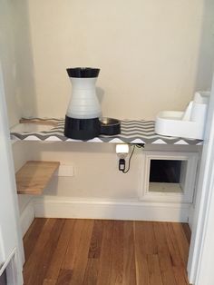 a white and black vase sitting on top of a shelf next to a microwave oven