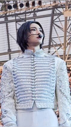 a man with black hair and makeup wearing a white outfit in front of a crowd