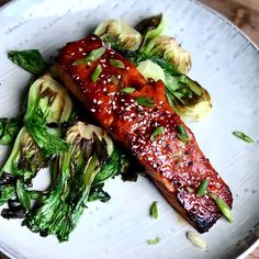 a white plate topped with meat and veggies on top of a wooden table