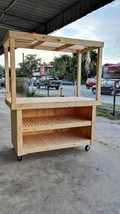 a wooden stand sitting under a metal roof next to a parking lot with cars parked in the background