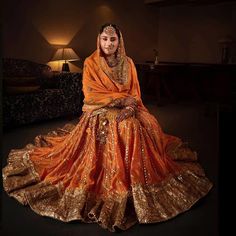 a woman in an orange bridal gown sitting on the floor with her arms crossed