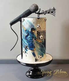 there is a cake with a soccer player on it and a microphone attached to the top