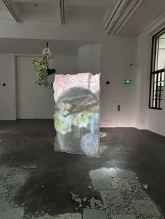 an empty room with broken glass on the floor and a painting hanging from the ceiling