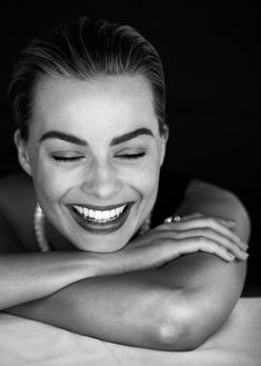 black and white photograph of a smiling woman with her arms folded over her chest, looking at the camera