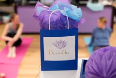 a purple bag sitting on top of a yoga mat next to two women in the background