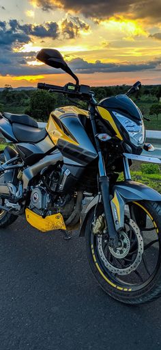 a yellow and black motorcycle parked on the side of the road at sunset or dawn