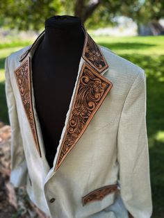 a white suit jacket with brown trims and an intricate design on the lapel