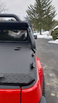 the back end of a red jeep parked in a parking lot with snow on the ground