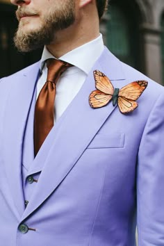 a man in a purple suit with a butterfly on his lapel