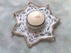 a white candle sitting on top of a doily